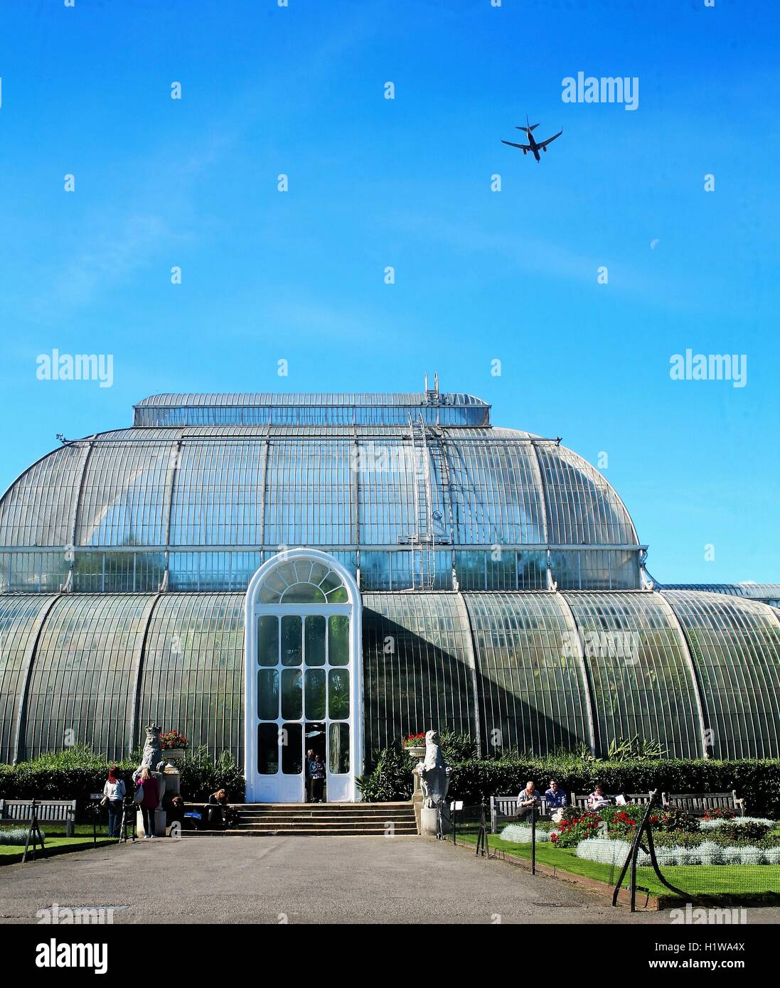 Large greenhouse in Kew Gardens, West London, with aeroplane flying