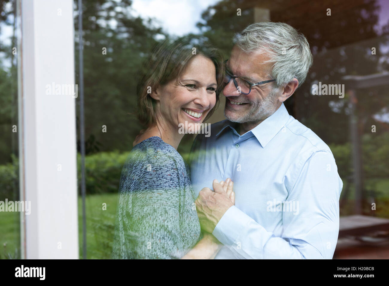 Happy mature couple behind windowpane Stock Photo