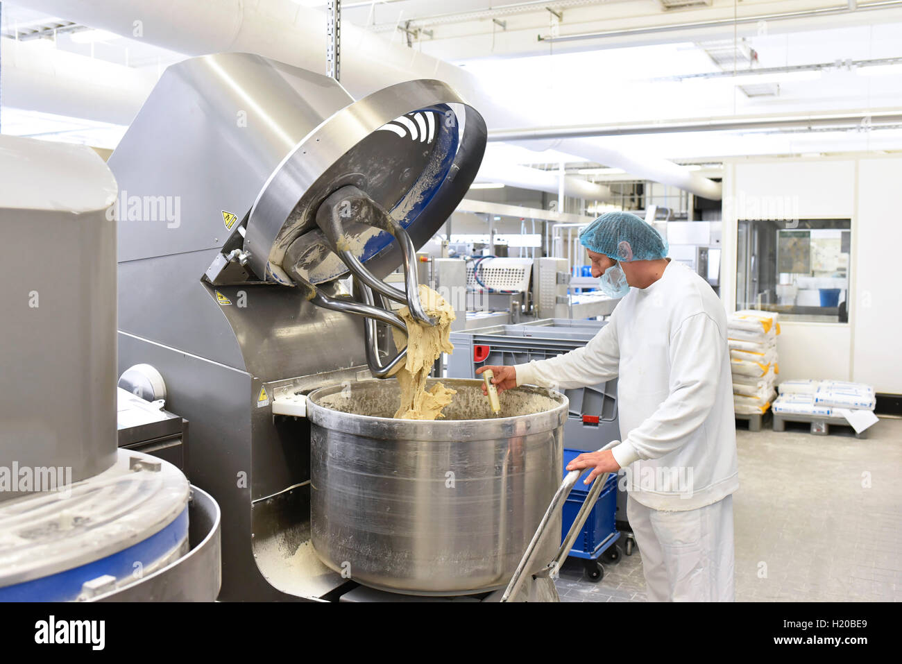 Worker at dough kneading machine in an industrial bakery Stock Photo