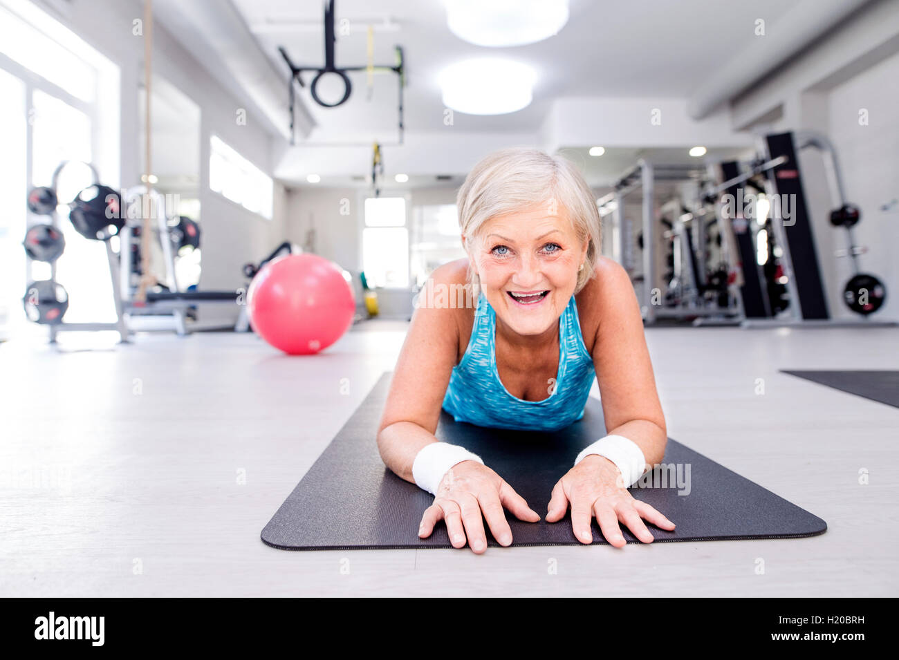 Smiling mature woman lifting up fitness ball in gym