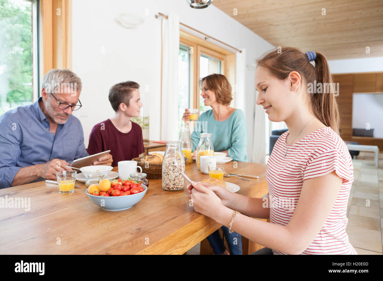 Family using portable devices during breakfast at home Stock Photo