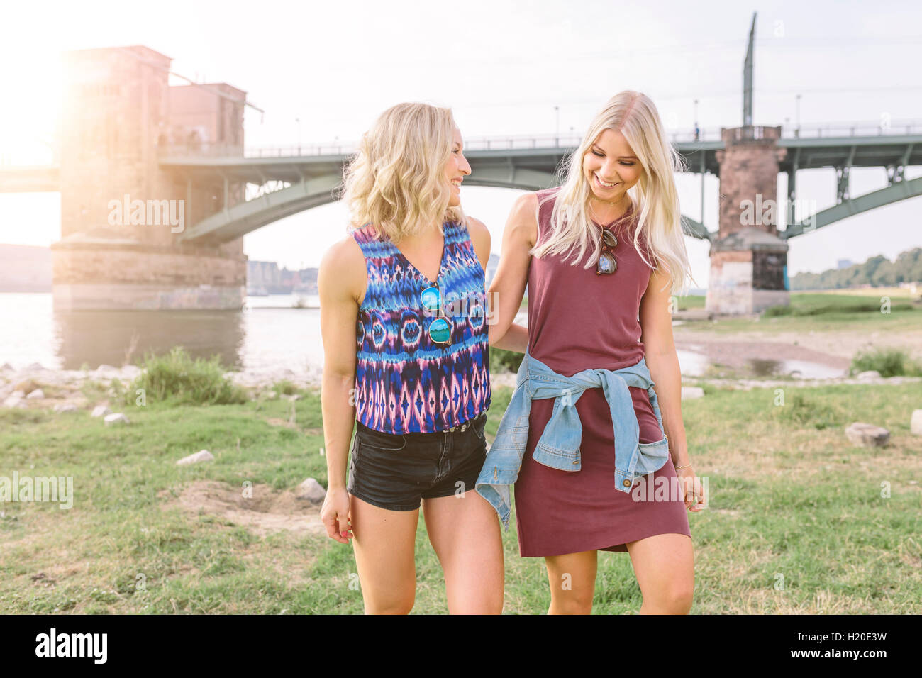 Two smiling young women walking at riverbank Stock Photo - Alamy