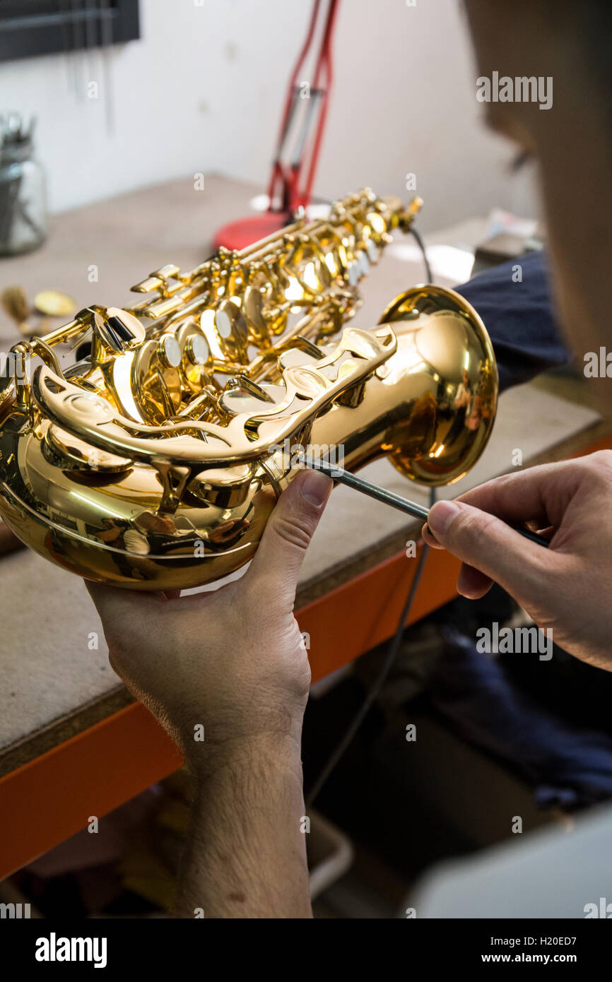 Instrument maker dismounting a saxophone during a repair Stock Photo