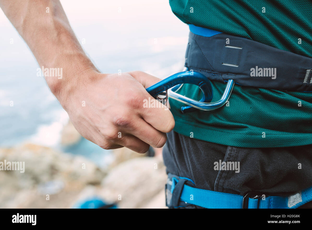 Close-up of climber placing a carabiner in his climbing harness Stock Photo
