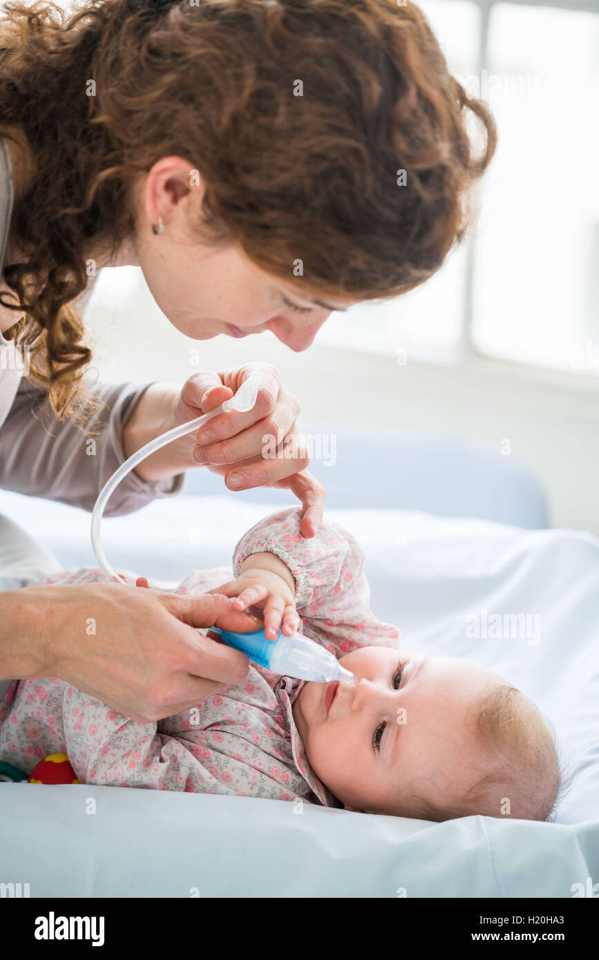 6 month old baby girl having his nose cleared with a nose-blower. Stock Photo