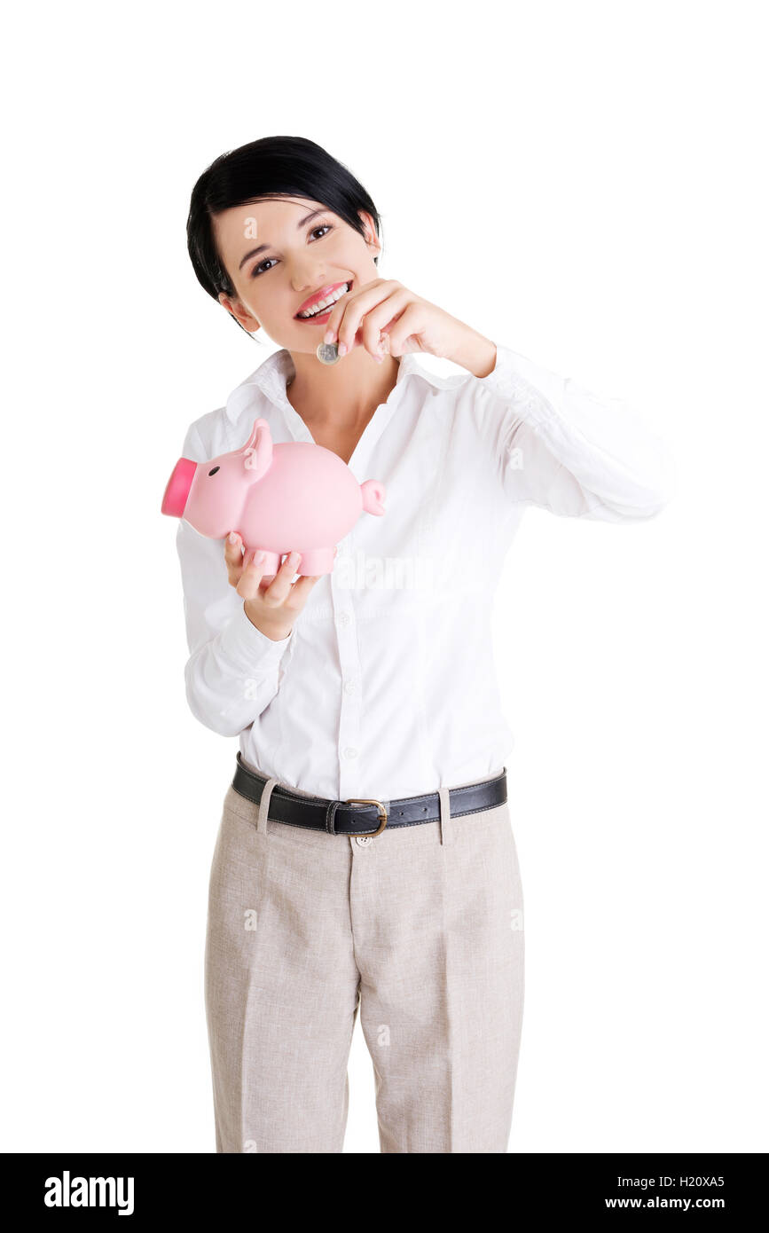 Businesswoman putting a coin into a piggy bank Stock Photo - Alamy