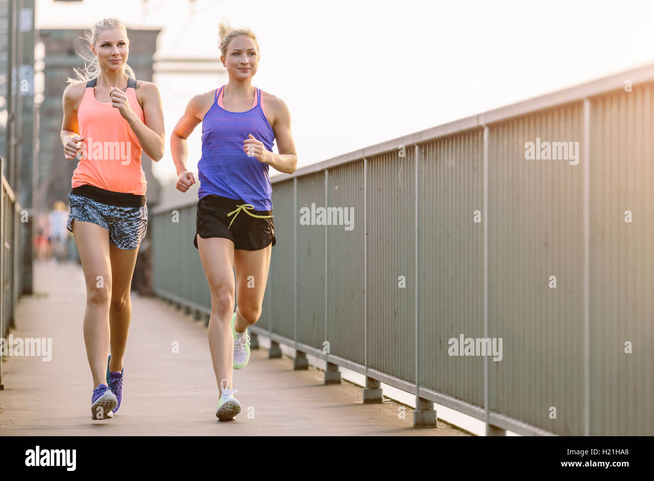 Two young women running on bridge Stock Photo