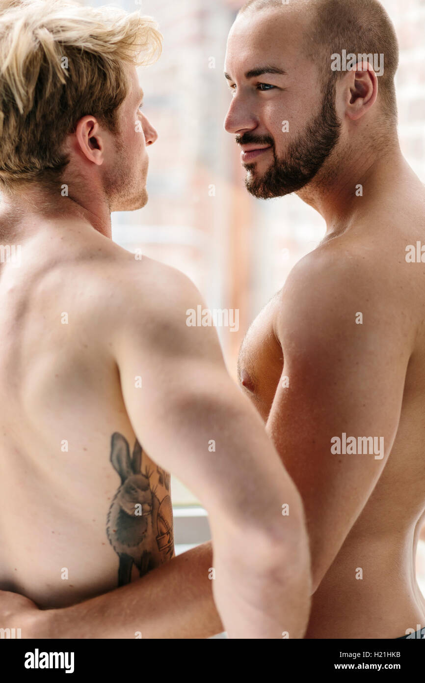 Gay couple embracing at window Stock Photo