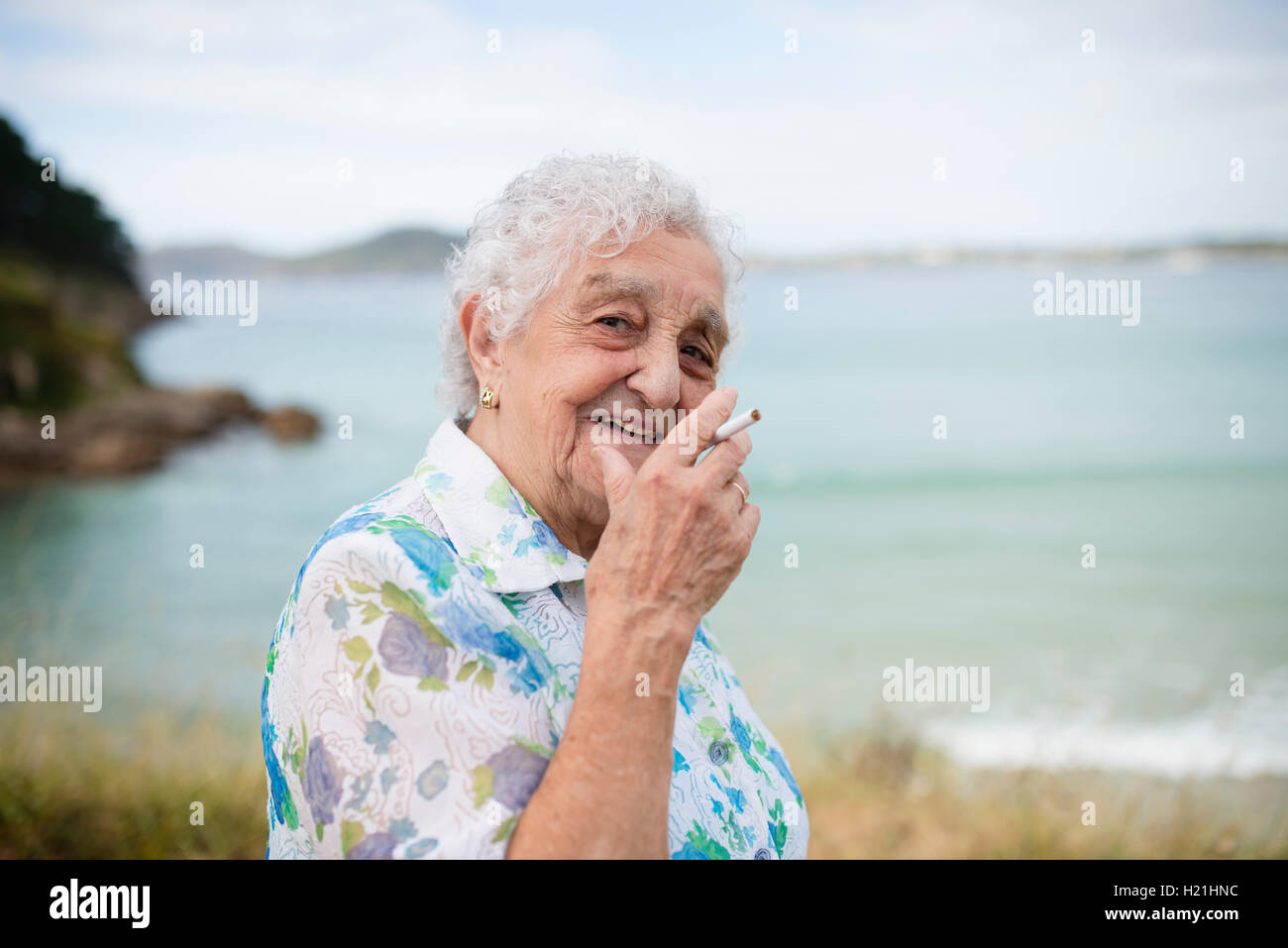Portrait of smiling senior woman with cigarette Stock Photo