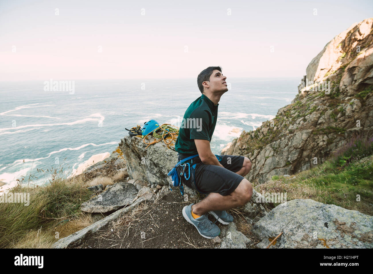 Climber sitting on a rock at the coast looking up Stock Photo
