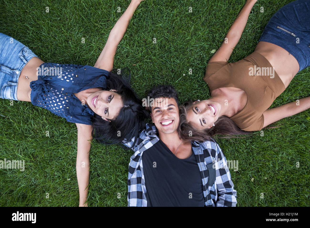 Three happy friends lying on meadow hi-res stock photography and images ...
