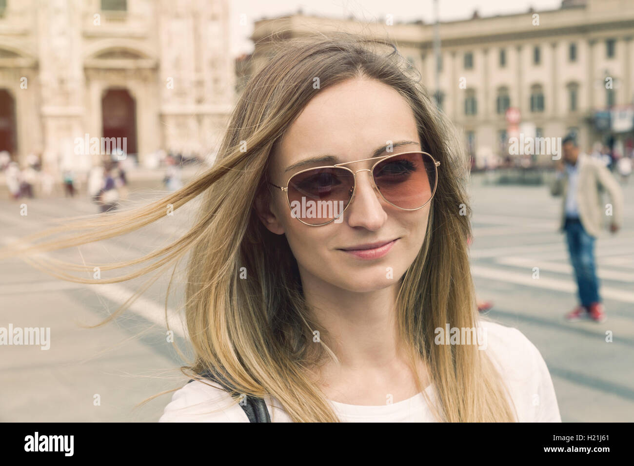 Italy, Milan, portrait of smiling blond tourist with sunglasses in
