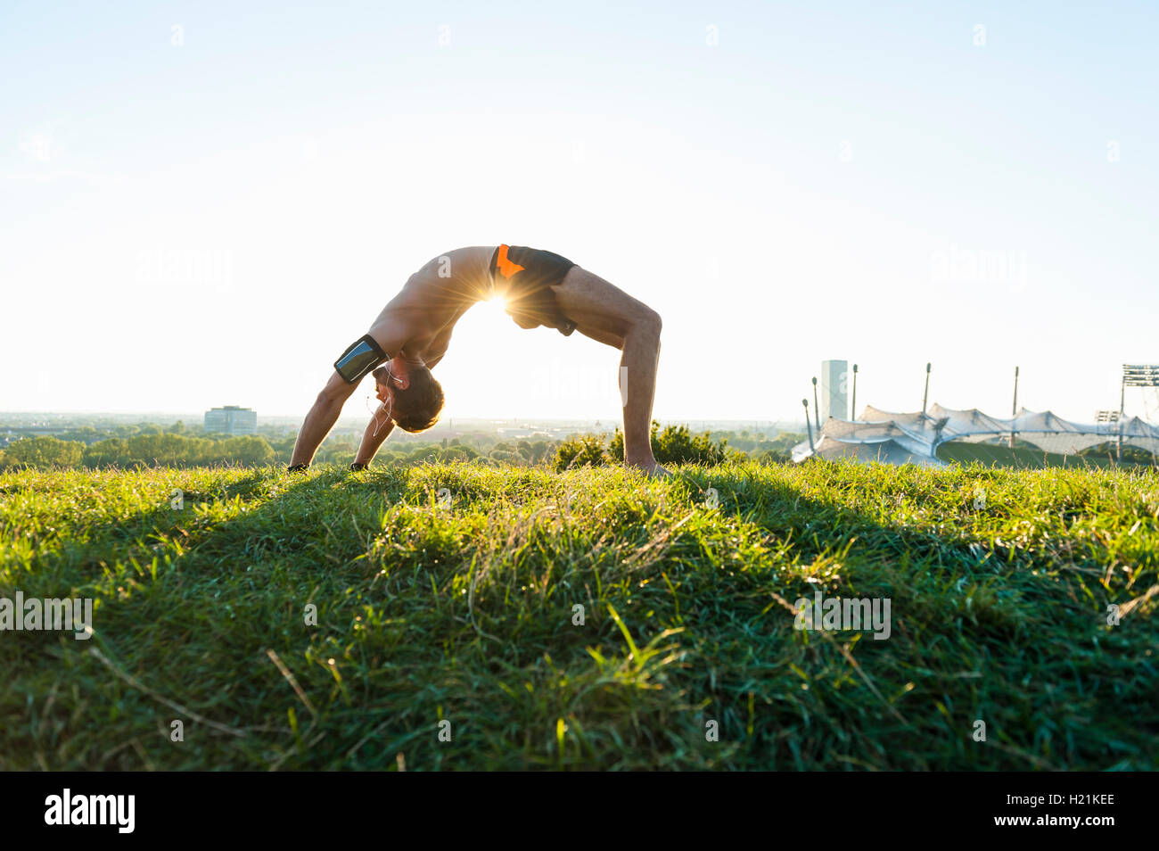 Man in bridge position on meadow in park Stock Photo