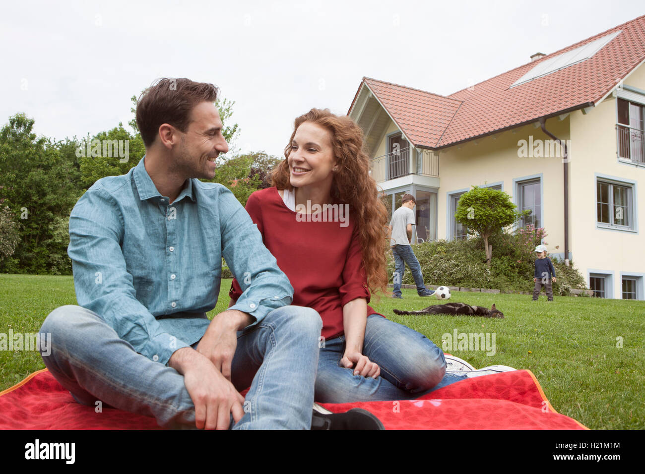 Smiling couple in garden with kids in background Stock Photo