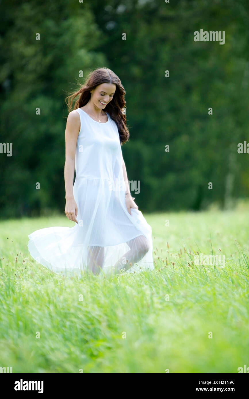 Happy woman wearing white summer dress walking on a meadow Stock Photo ...