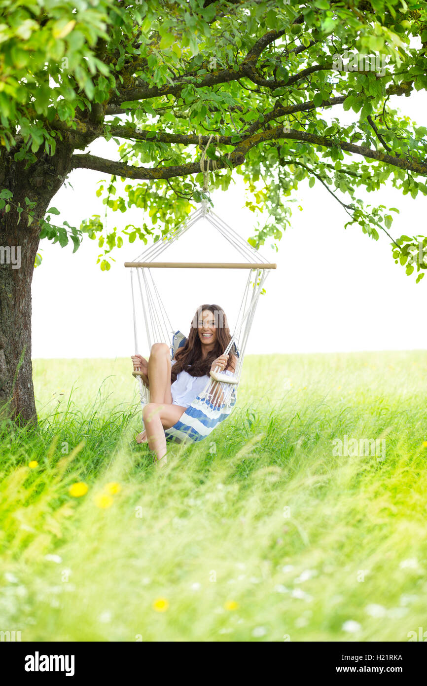 Happy woman relaxing in a hanging chair under a tree Stock Photo - Alamy