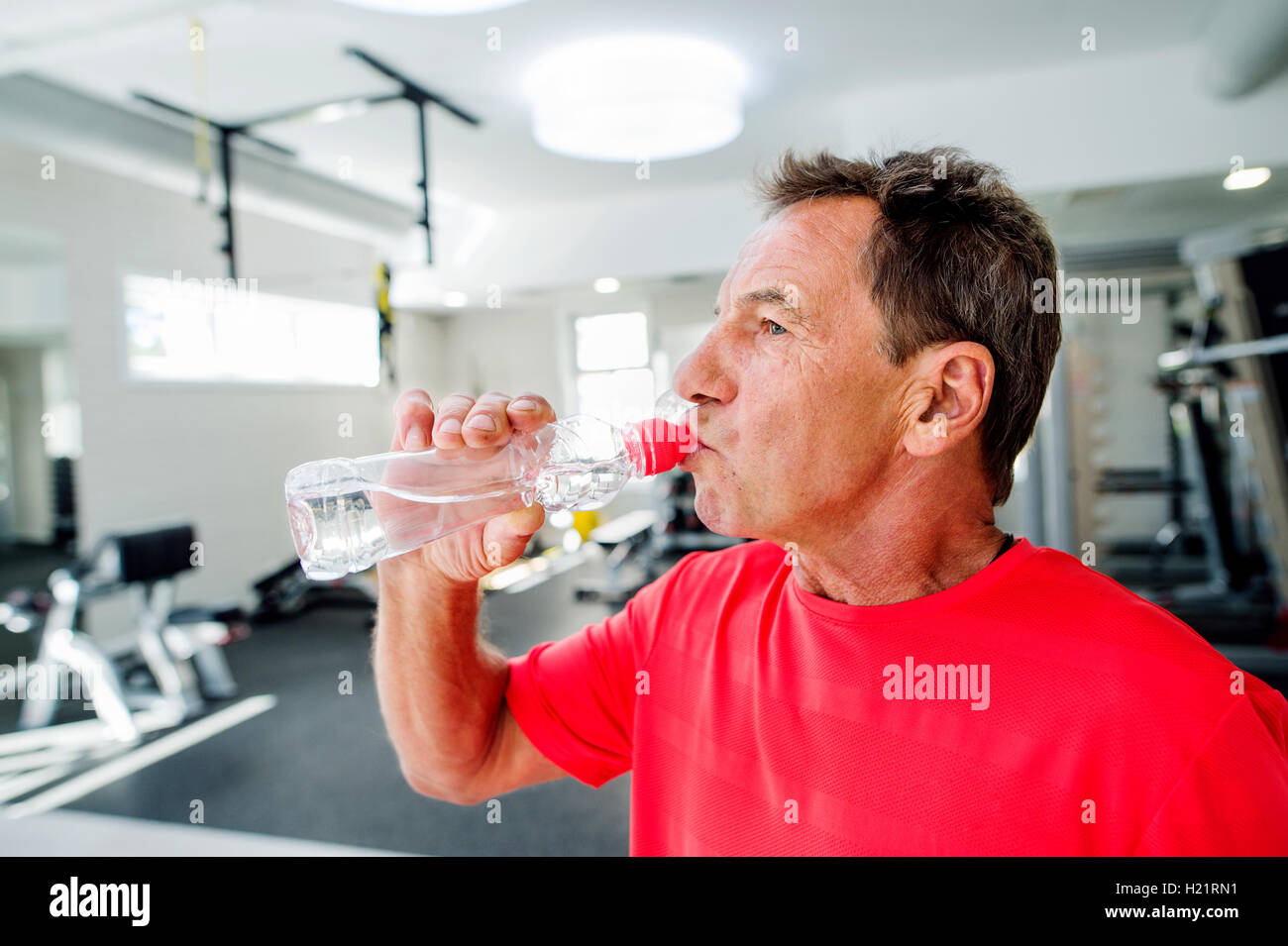 Senior man in fitness gym drinking water from bottle Stock Photo - Alamy