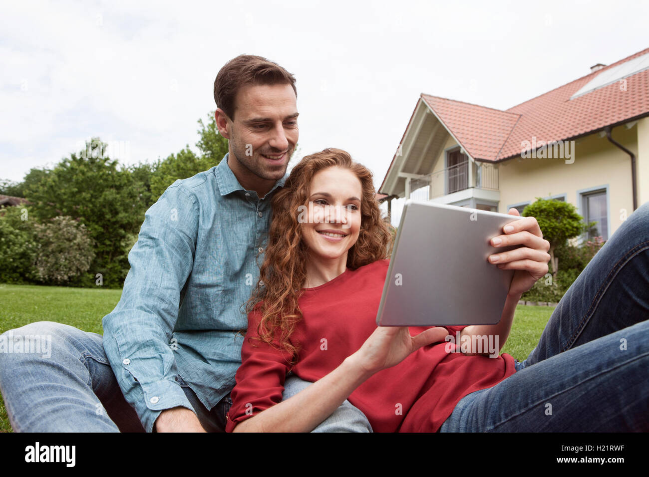 Smiling couple sitting in garden using tablet Stock Photo