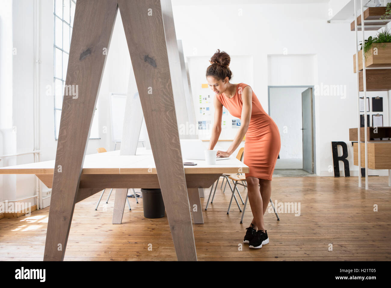 Woman standing at office desk using laptop Stock Photo
