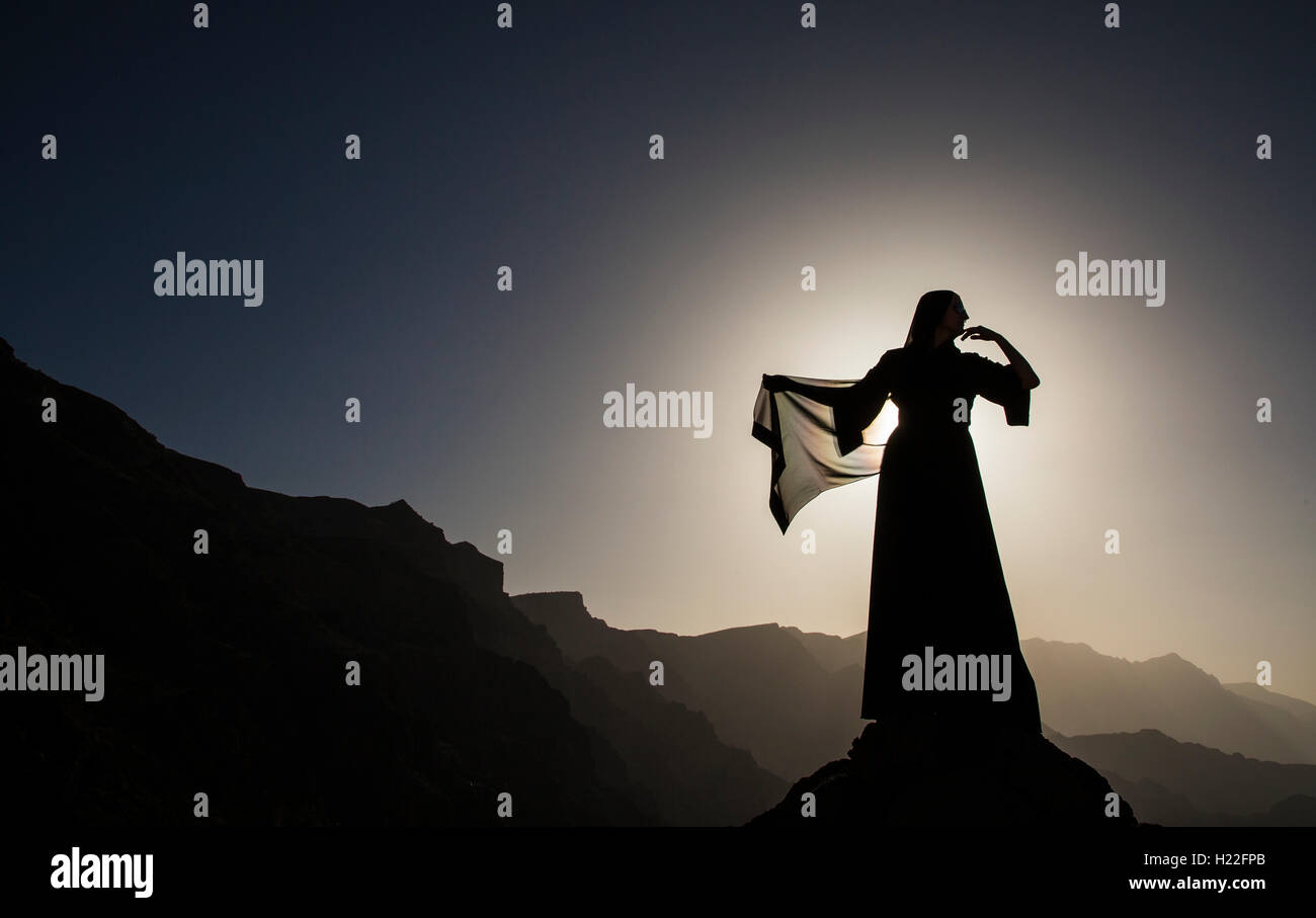 a woman in traditional Emirati dress (abaya) in mountains Stock Photo