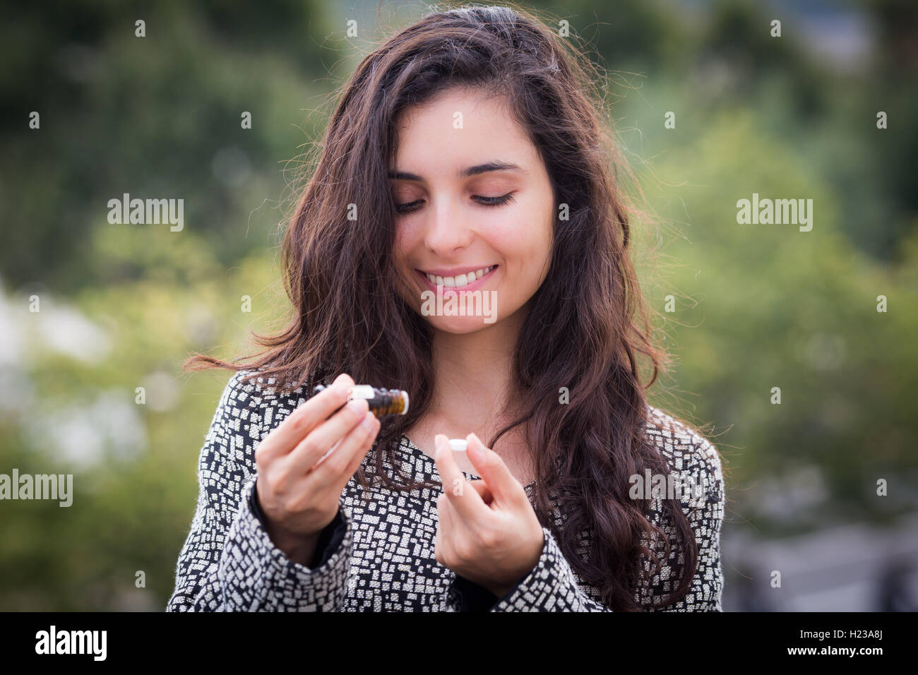 Woman applying essential oil on a neutral pill. Stock Photo