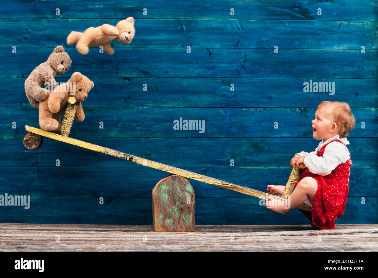 Three-year-old girl with teddy bear on seesaw, Austria Stock Photo - Alamy