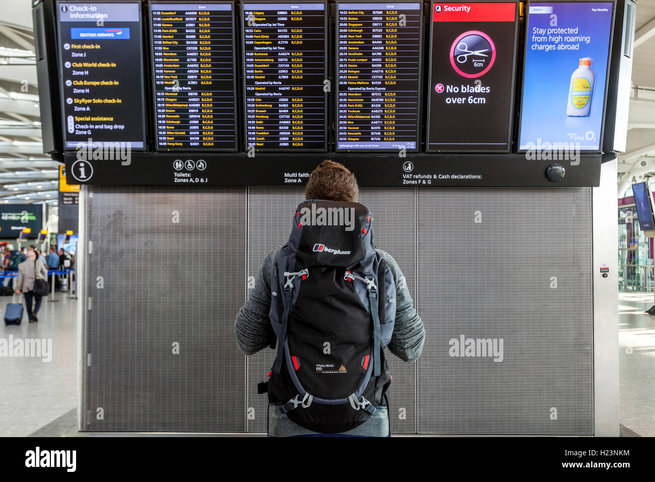 A Young Man Looking At A Departure Board, Heathrow Airport, London, UK Stock Photo