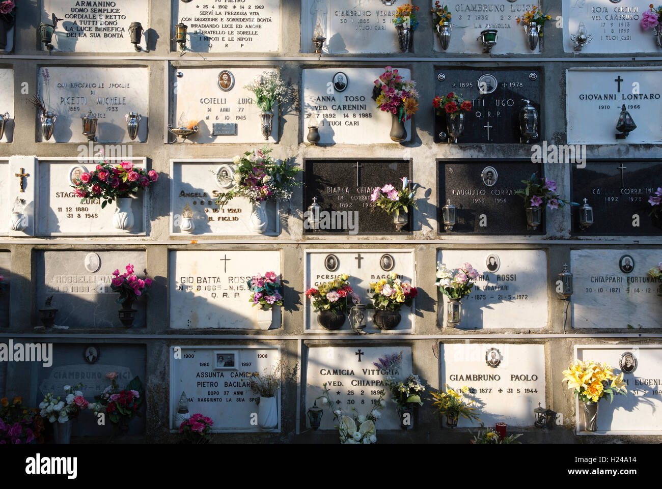 Italian hillside cemetery with individual plaques flowers and