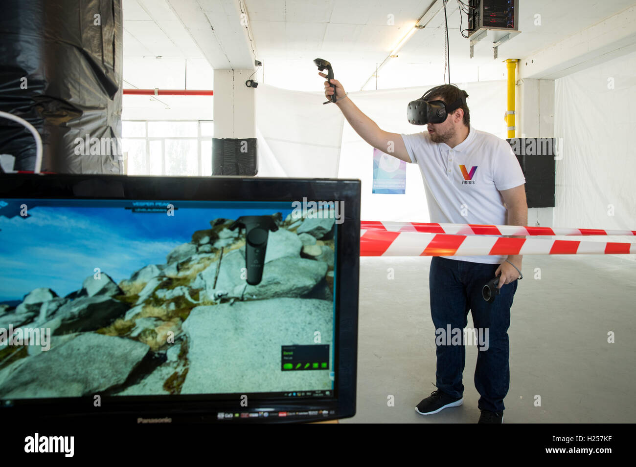 Nuremberg, Germany. 13th Sep, 2016. Aydin Tutkun, programmer at the Nuremberg start-up business 'Virtues', acts in a virtual world while wearing virtual reality glasses, two controllers for the hands and headphones in Nuremberg, Germany, 13 September 2016. The screen on the left shows the picture from his VR glasses. Virtual realities fascinate many people, but not all can afford the expensive equipment. The company 'Virtuis' wants take advantage of this. PHOTO: DANIEL KARMANN/dpa/Alamy Live News Stock Photo