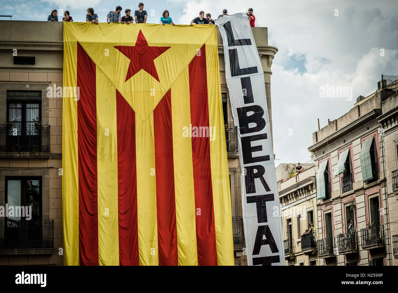 Barcelona, Spain. 24th September, 2016:  Pro-independence supporters hang a giant 'estelada' flag on the facade of a building facing the St Jaume Place demanding 'freedom' during the local 'Castellers' day at the Merce 2016 Credit:  matthi/Alamy Live News Stock Photo