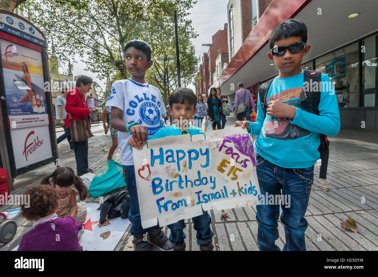 London, UK. 24th September 2016. 'Ismail's kids' arrive holding a poster they have just made for the party at the weekly street stall on Stratford Broadway to celebrate the third anniversary of the fight against Newham Council after 29 young mothers stood together to fight against their eviction from the Focus E15 hostel, refusing to accept being moved out of London, cut off from families and communities and demanding to be allowed to continue to live in the area they knew as home. Ismail's family were supported by Focus E15 when evicted. Peter Marshall/Alamy Live News Stock Photo