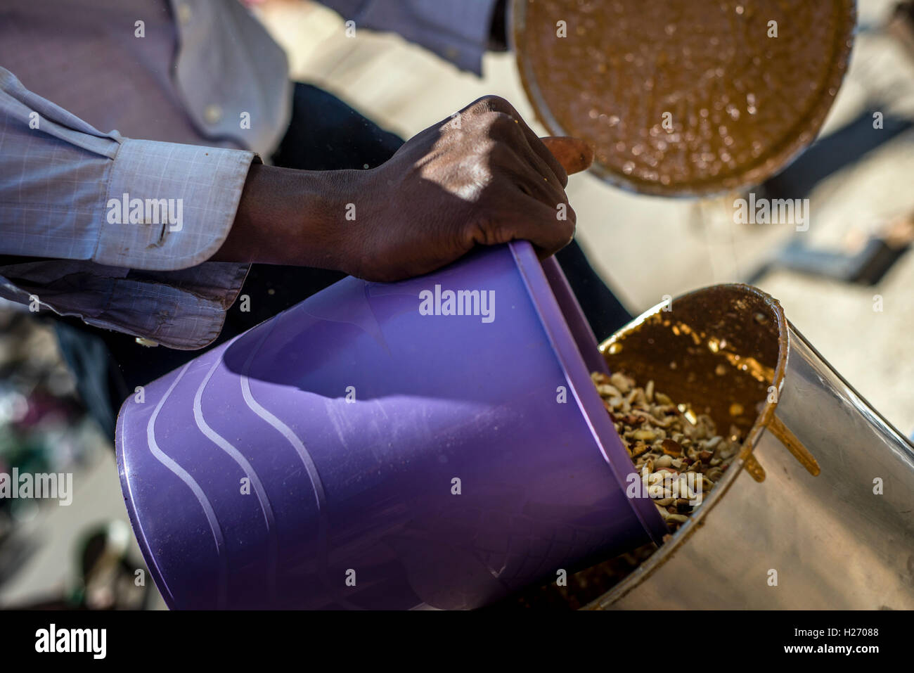 A man makes peanut butter for sell at the market in Lusaka, Zambia Stock Photo