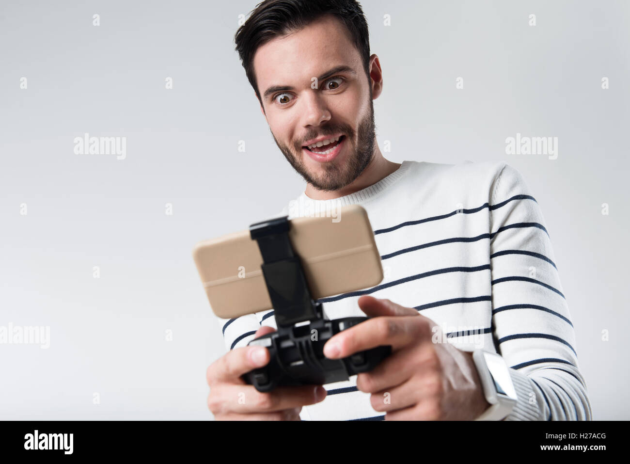 Energized bearded man using portable gamepad Stock Photo
