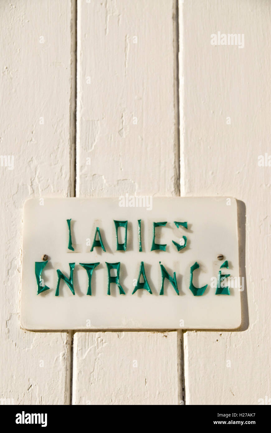 old weatherbeaten Ladies entrance door sign, The plastic writing has shrunk and become detached from the door Stock Photo