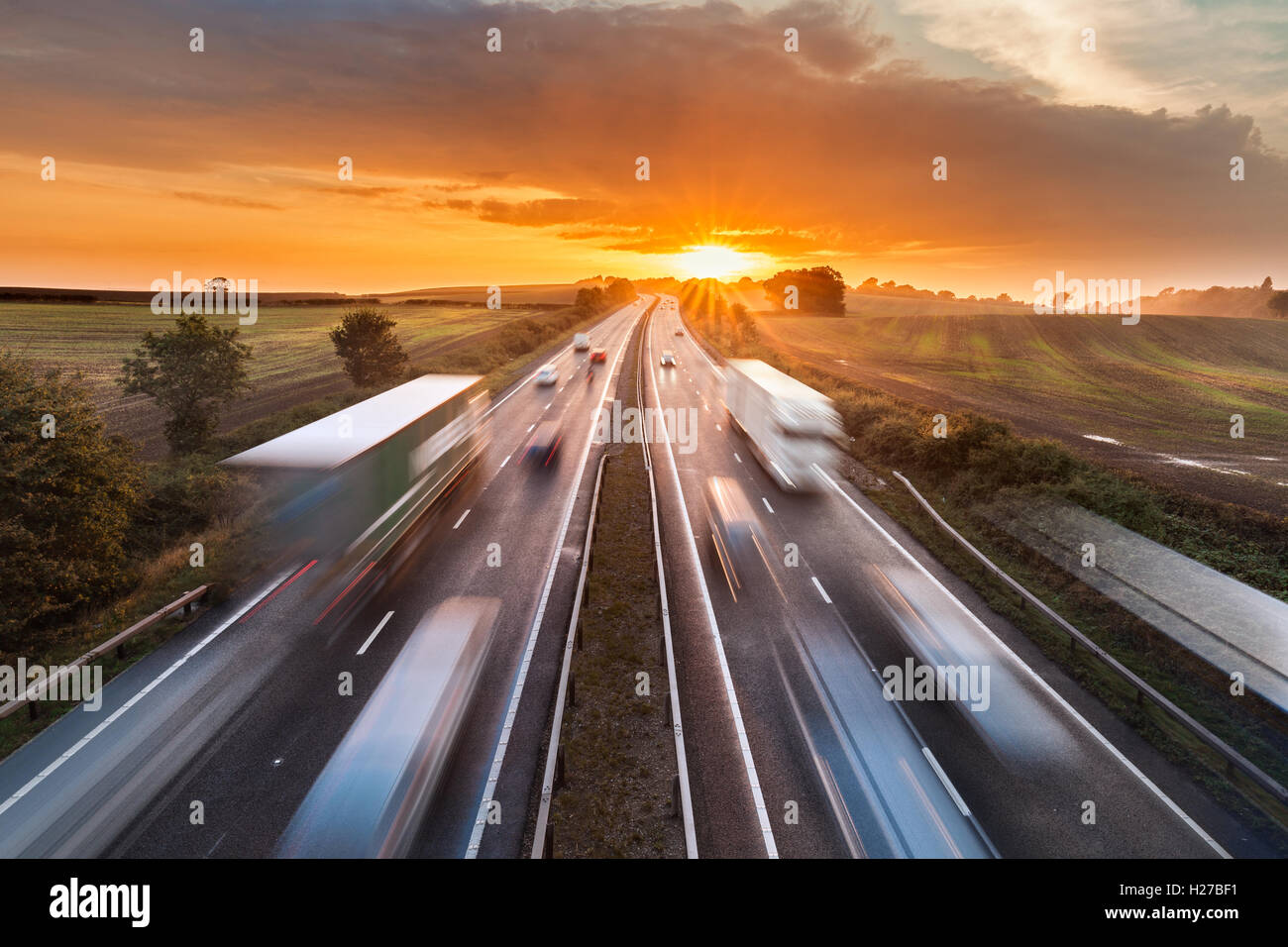 Trucks and Cars in Motion on Busy Motorway at Sunset Stock Photo