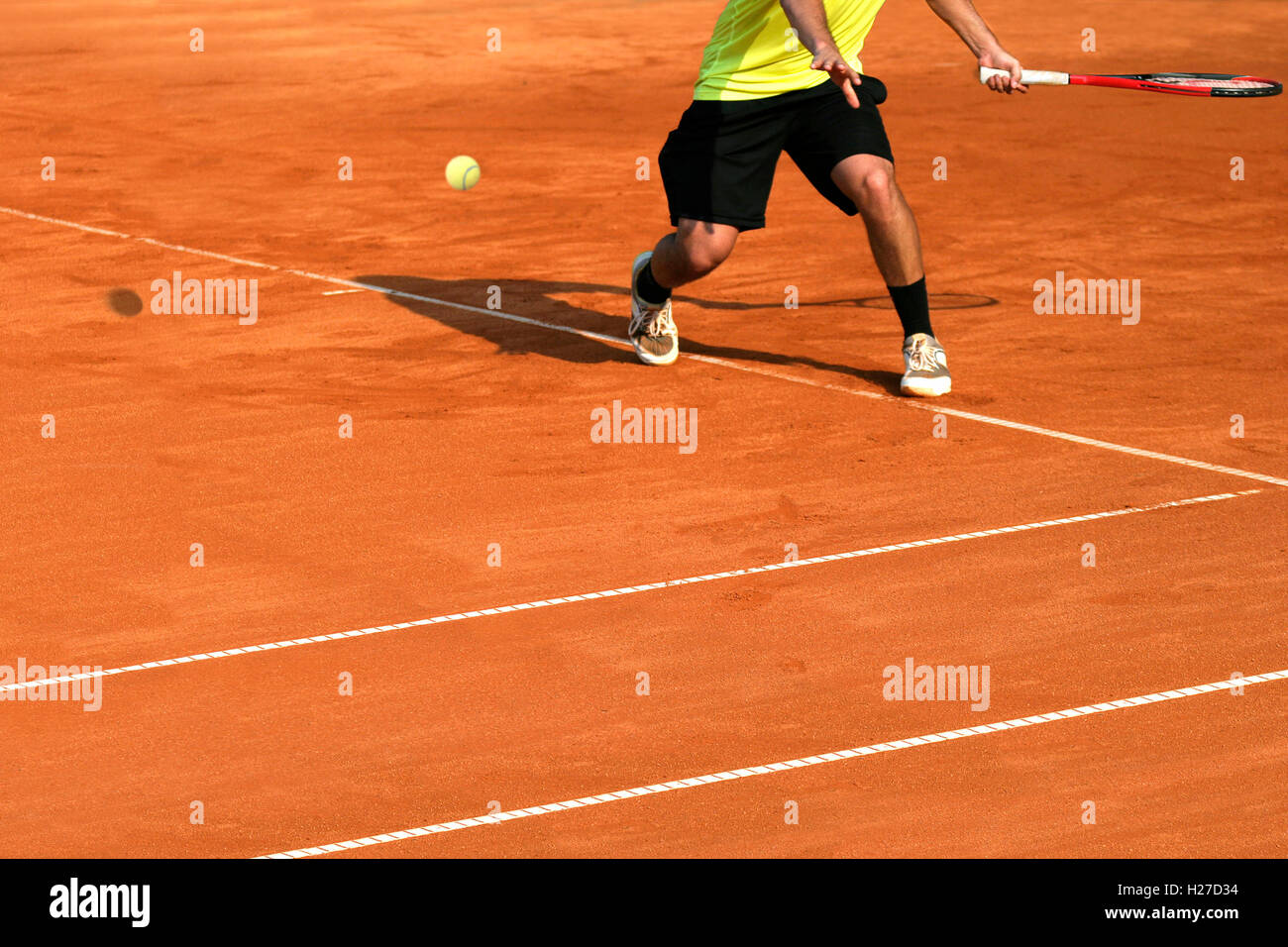 Male tennis player in action on the court on a sunny day Stock Photo