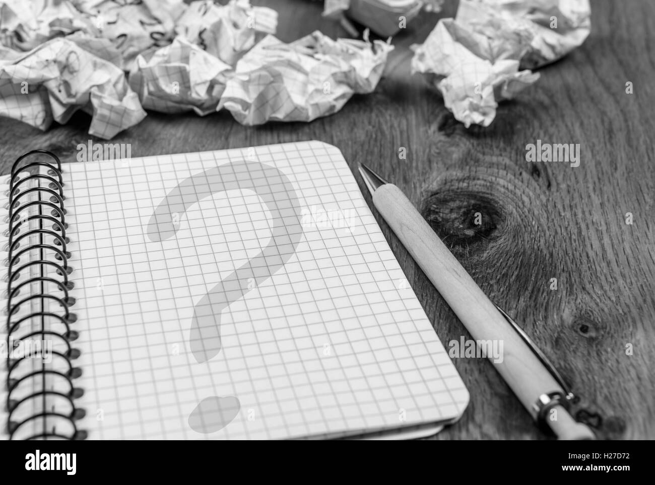 Graphic notebook with question mark on its page and thrown drafts on ...