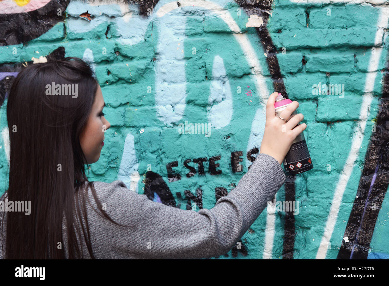 Portrait of young latin woman drawing graffiti with spray paint on ...