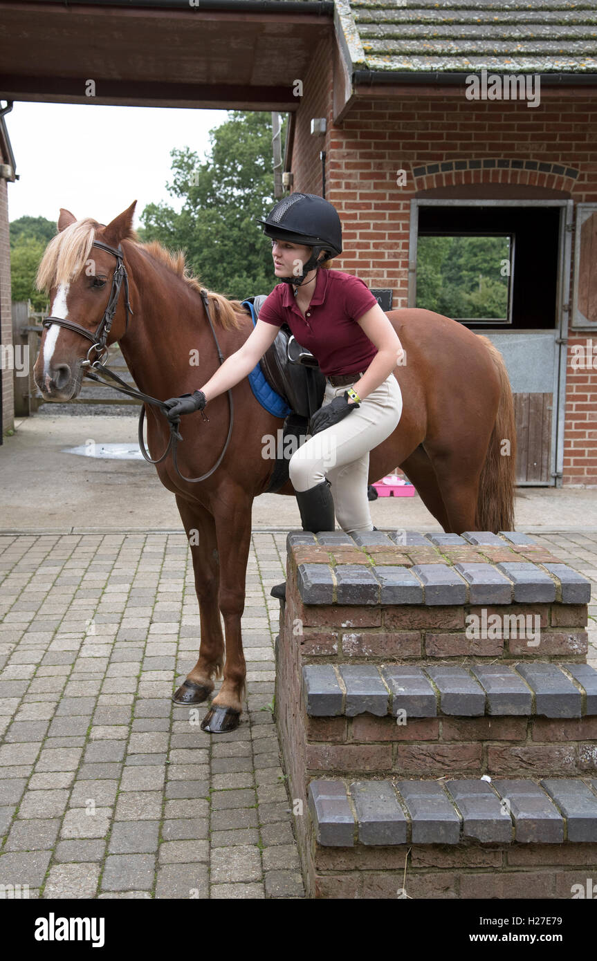 Young rider using a mounting block Teenager using the steps on a mounting block to get into