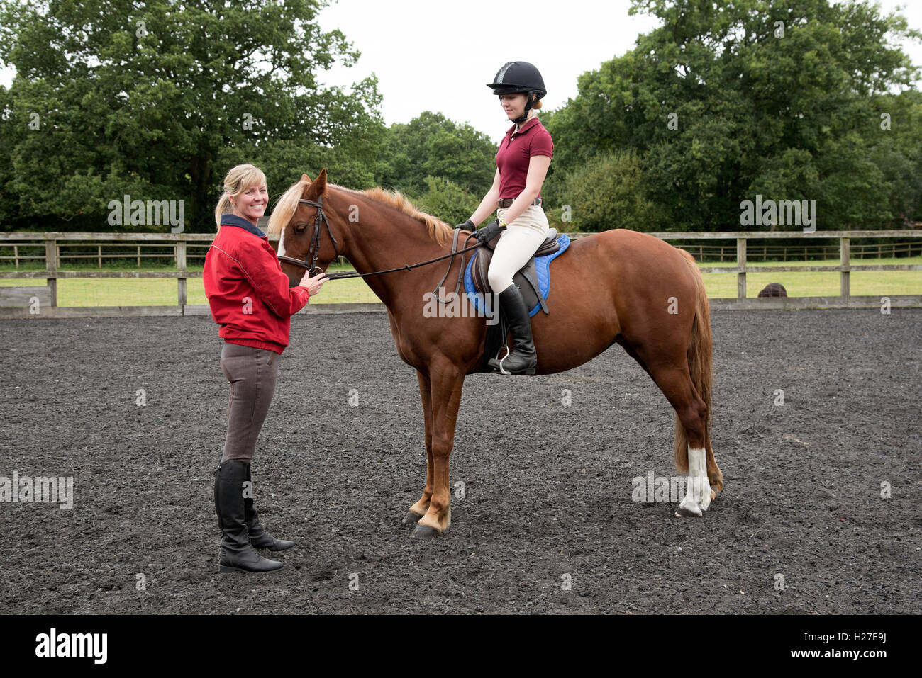 Young pony rider sitting in the saddle. The teenage pupil learning to ride with the instructor Stock Photo