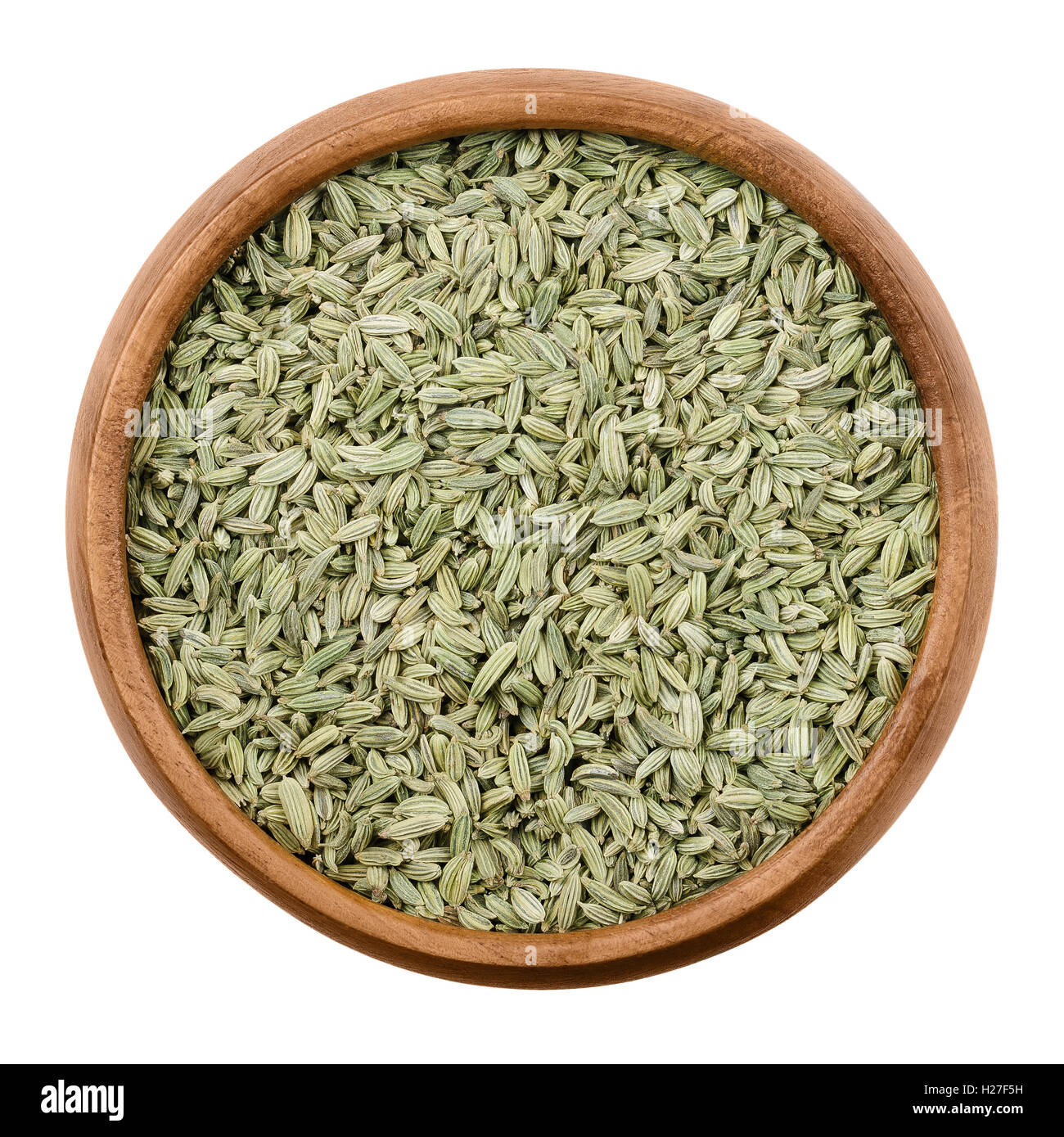 Fennel seeds in a wooden bowl on white background. Dried fruits of Foeniculum vulgare, an aromatic and flavorful herb. Stock Photo