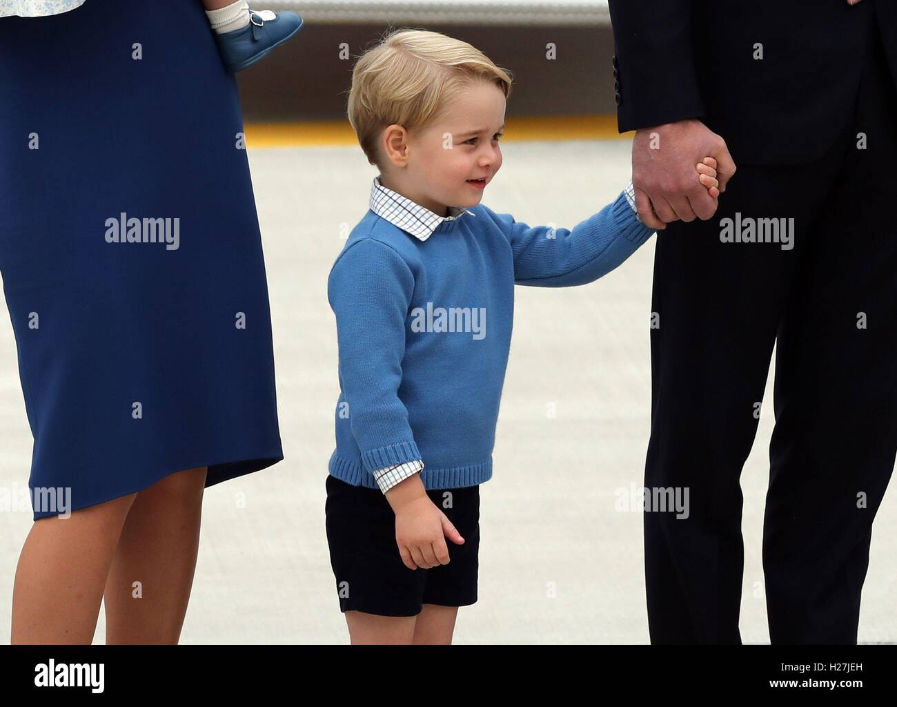 Prince George stands between his parents the Duke and Duchess of Cambridge as the Royal Party, including his sister Princess Charlotte, arrive at Victoria International Airport, in Victoria, Canada, on the first day of their official tour of Canada. Stock Photo