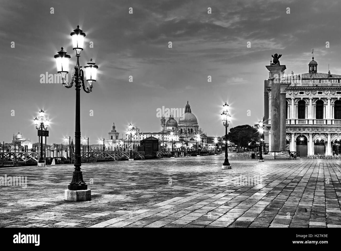 San Marco square piazza in Venice at sunrise with illuminated street lights in black-white image. Stock Photo