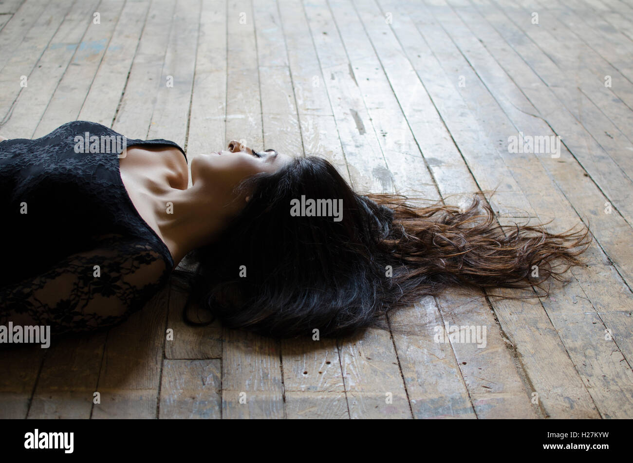Woman With Long Dark Hair Laying Down On The Floor Stock Photo
