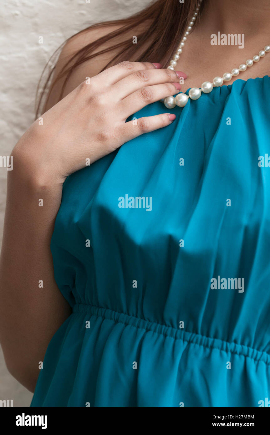 Close up of a young woman wearing a blue dress and pearl necklace Stock Photo