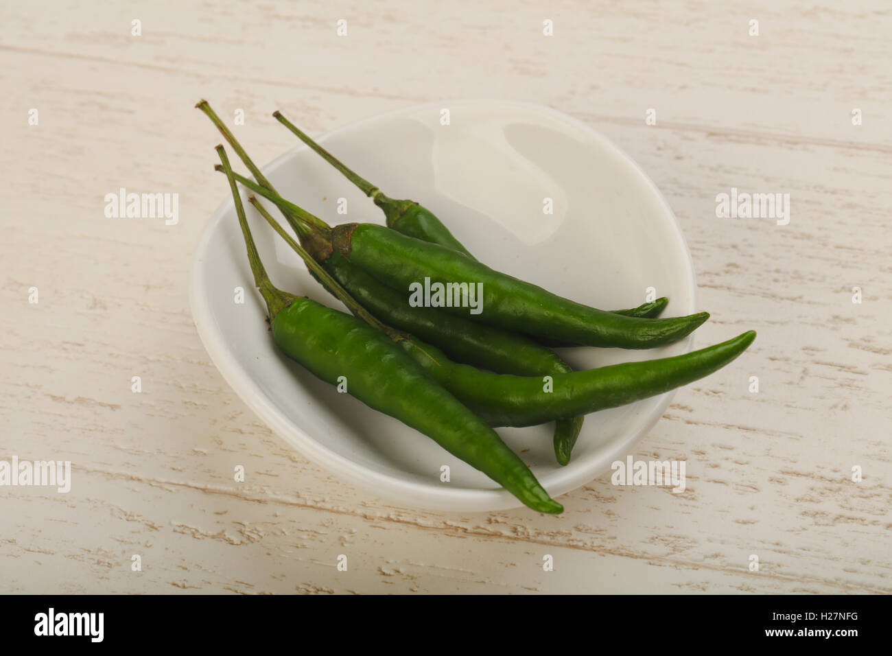 Green chili peppers heap in the bowl on wood background Stock Photo - Alamy
