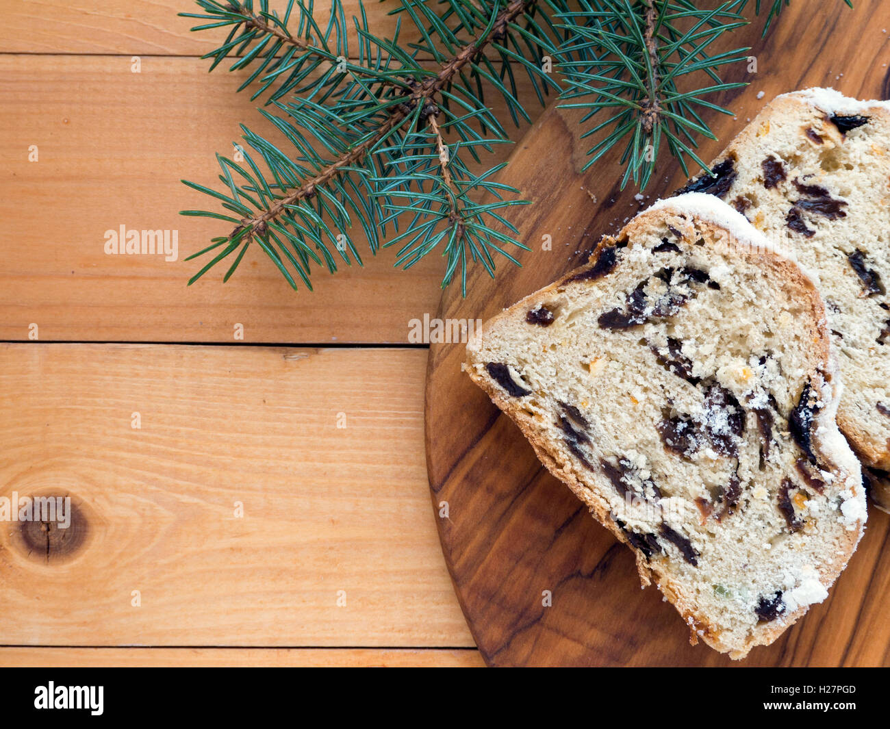 Stollen German Christmas cake on the textured wooden board and blue spruce branches on the  wooden planks Stock Photo