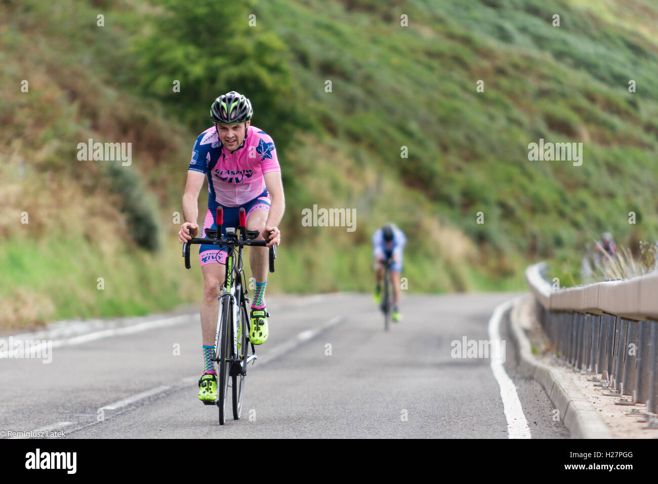 Speeding professionally dressed cyclists on the asphalt during the competition in Scotland Stock Photo