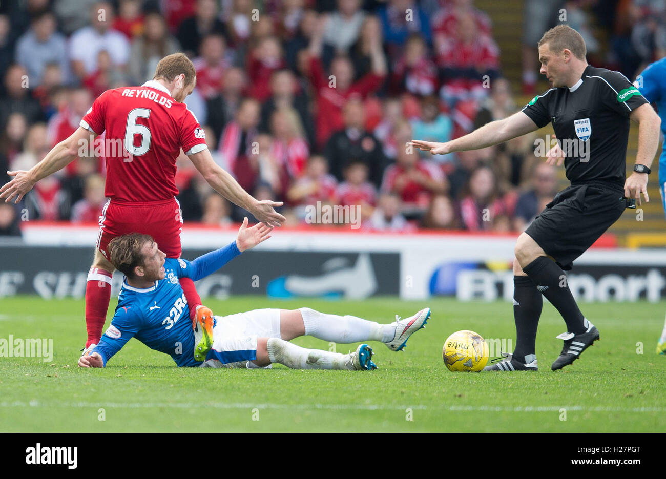 Referee John Beaton walks up to Rangers' Andy Halliday (on ground) from Aberdeen's Mark Reynolds during the Ladbrokes Scottish Premiership match at the Pittodrie Stadium, Aberdeen. Stock Photo