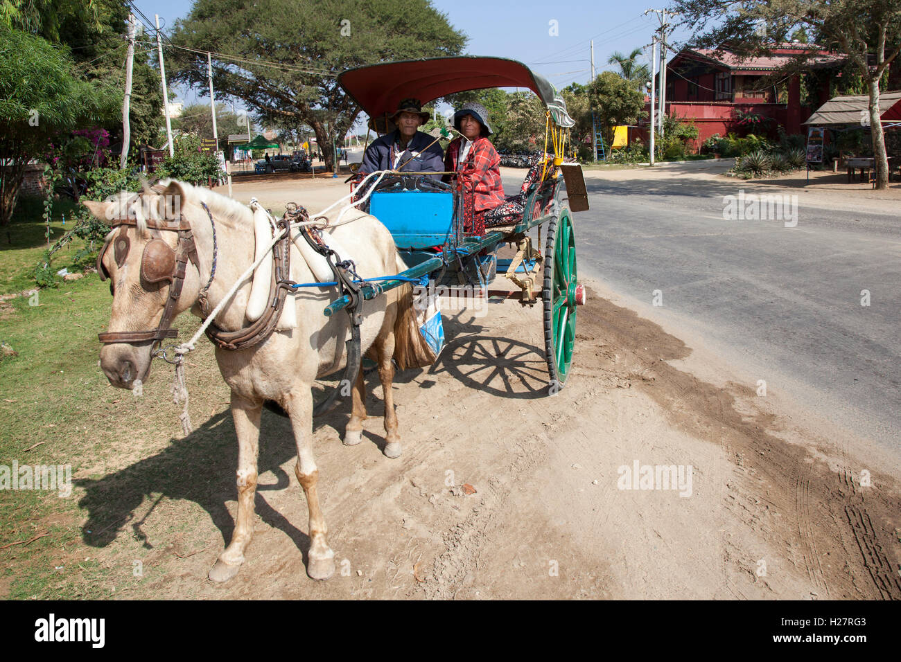 An old and faded calash with a couple of coach drivers waiting for passengers, at New Bagan (Myanmar). Vieille calèche à Bagan. Stock Photo